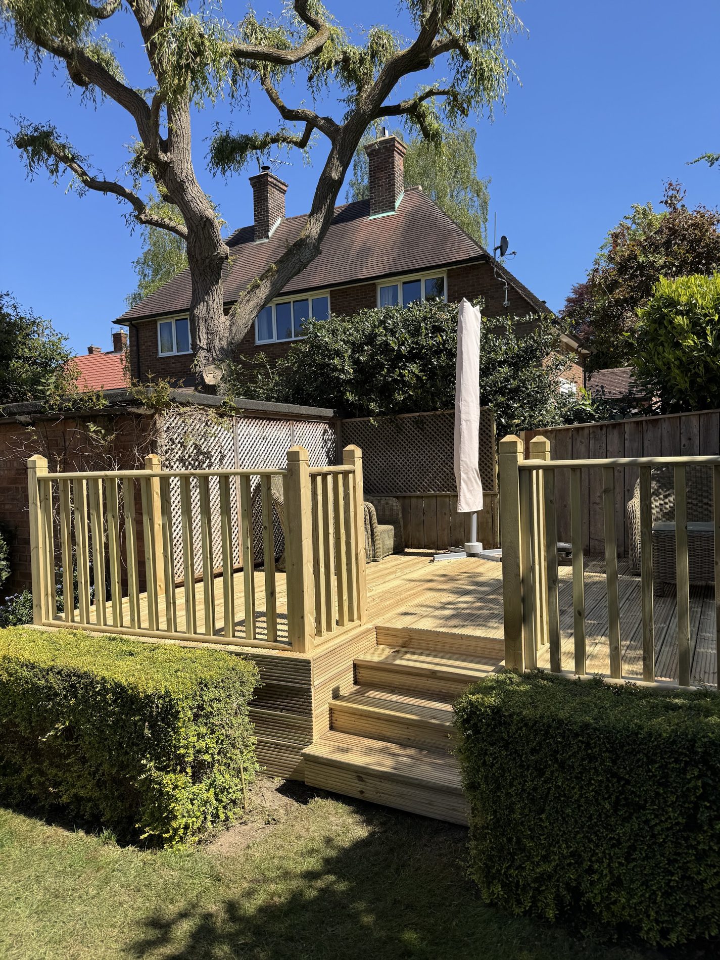 A raised deck with a balustrade and steps in front of a pair of semi-detached houses