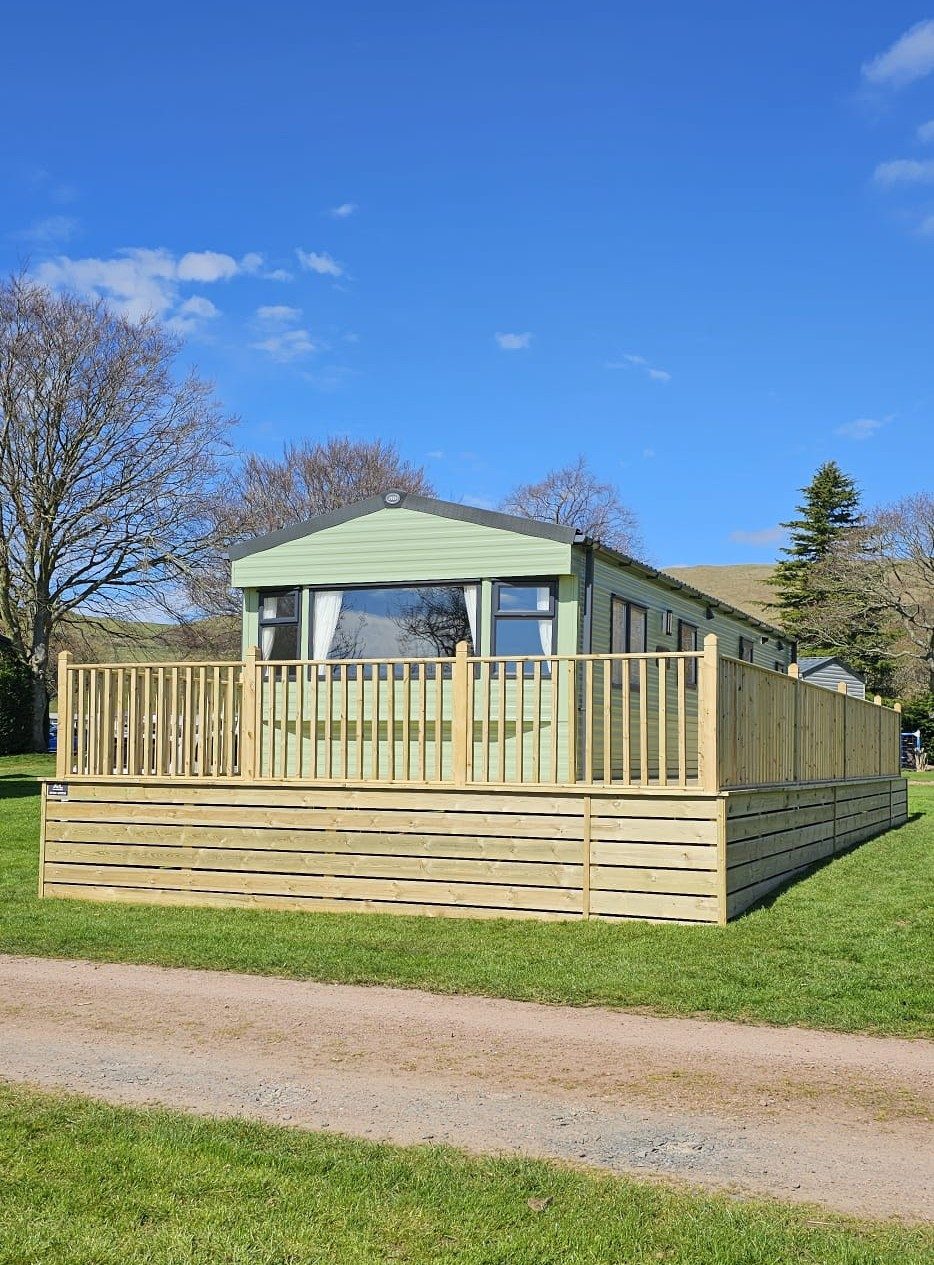 A static caravan raised on a new timber deck with a balustrade